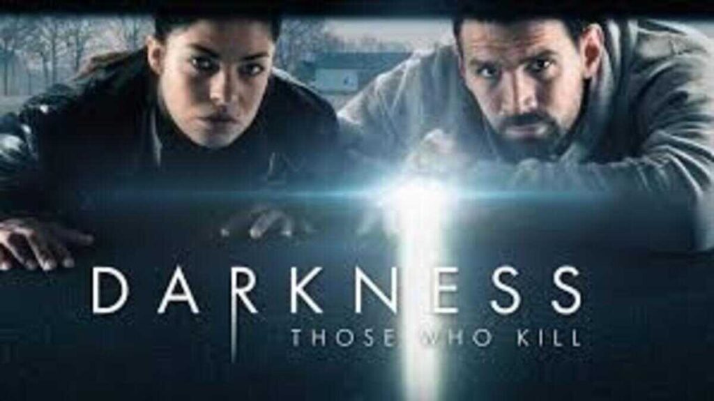 Pôster promocional da série de suspense Darkness Those Who Kill. Em primeiro plano, um homem e uma mulher estão debruçados sobre uma superfície escura, olhando fixamente em direção ao espectador com expressões sérias e concentradas. Entre eles, um forte feixe de luz vertical de uma lanterna corta a escuridão, iluminando parcialmente seus rostos. Ao fundo, uma paisagem nebulosa e acinzentada com árvores desfolhadas sugere um clima frio. Na metade inferior, o título Darkness aparece em letras maiúsculas brancas de tamanho grande, seguido pelo subtítulo Those Who Kill em letras menores.