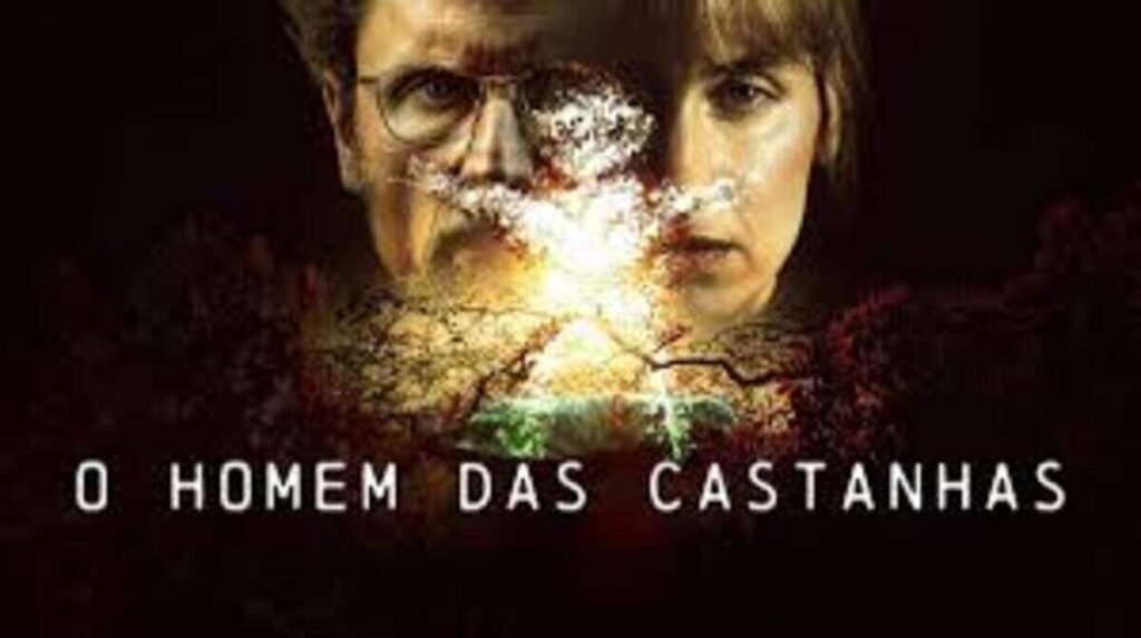 Pôster promocional da série de suspense O Homem das Castanhas. Em um fundo completamente escuro, os rostos em close de um homem de óculos e uma mulher aparecem parcialmente na penumbra com expressões sérias e preocupadas. Sobrepostos ao centro dos rostos, há o contorno brilhante e iluminado de um boneco feito de castanhas e galhos secos, que parece emanar uma luz intensa de uma explosão ou chama. Na metade inferior, o título O Homem das Castanhas está escrito em letras maiúsculas brancas, limpas e espaçadas.