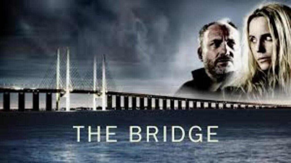 Pôster promocional da série The Bridge. A composição mostra uma longa ponte estaiada iluminada que cruza o mar sob um céu noturno e nublado. No canto superior direito, os rostos dos dois protagonistas surgem de forma esfumaçada em meio às nuvens: um homem barbudo com olhar sério e uma mulher loira expressando preocupação. Na metade inferior, sobre as águas escuras, o título The Bridge está escrito em letras maiúsculas brancas e finas.