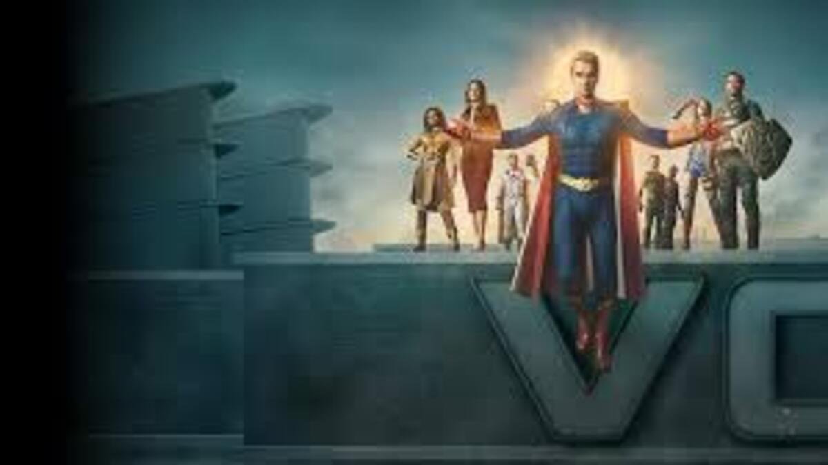Cena promocional da série The Boys em ambiente externo e nublado. No centro, o personagem Capitão Pátria flutua no ar com os braços abertos em uma postura messiânica, vestindo seu uniforme azul clássico com capa vermelha, enquanto uma luz dourada e brilhante emoldura sua cabeça como uma aura. Ele está posicionado à frente de uma estrutura de concreto cinza que exibe parte do logotipo da empresa Vought. Ao fundo, fora de foco, os demais integrantes do grupo Os Sete observam a cena alinhados lado a lado.