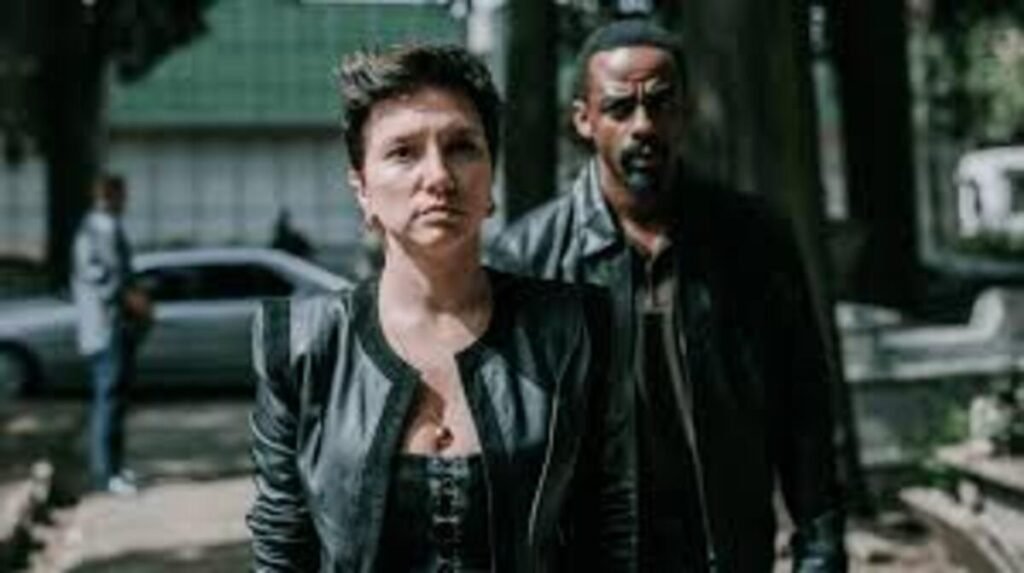 Cena da série brasileira Impuros destacando os protagonistas em um momento de tensão. Os personagens aparecem com figurinos de couro em um cenário externo, reforçando o clima de drama e suspense da produção.