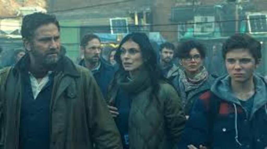 Protagonistas caminhando apreensivos em meio a uma multidão de sobreviventes em cena de ficção científica do filme Destruição Final. A imagem promocional destacando o clima de drama pós-apocalíptico e sobrevivência familiar é excelente para ilustrar críticas de cinema, análises de enredo e novidades sobre grandes blockbusters no blog.