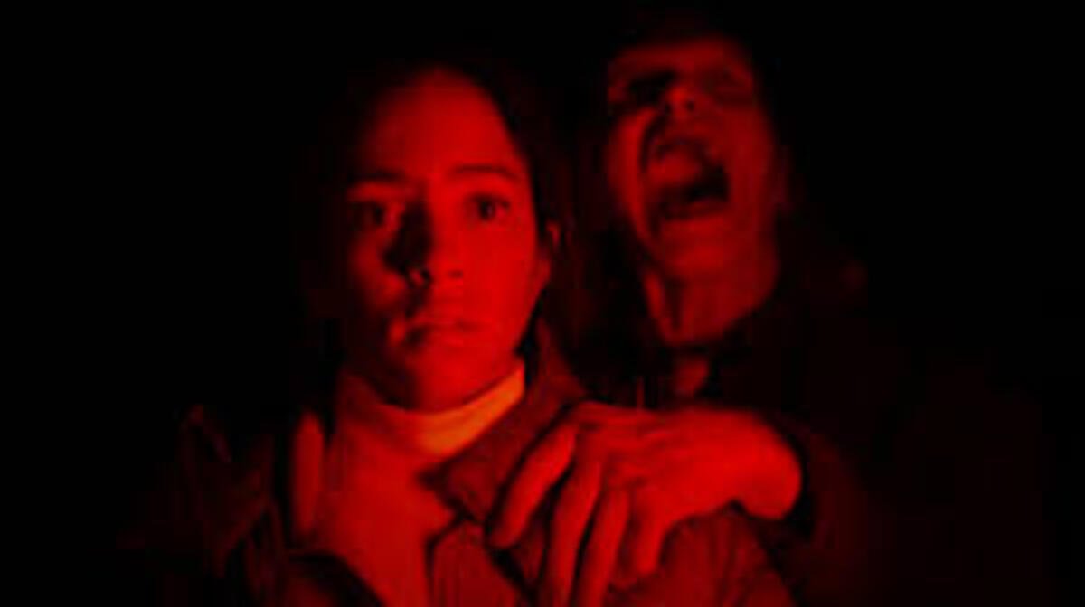 Cena assustadora sob iluminação vermelha expressionante no filme Passageiro do Mal. A imagem promocional focada no suspense psicológico e no clima de perseguição é ideal para ilustrar críticas de cinema de terror, análises de grandes sustos e novidades sobre lançamentos do gênero no site.