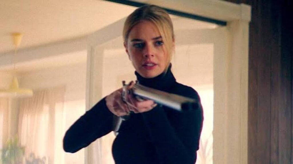 Protagonista armada com espingarda em momento de confronto e defesa na trama de suspense do filme Por Cima do Seu Cadáver. A imagem promocional focada no subgênero de invasão domiciliar e na evolução da personagem principal é ideal para ilustrar críticas de cinema, análises de thrillers e listas de filmes de sobrevivência no blog.