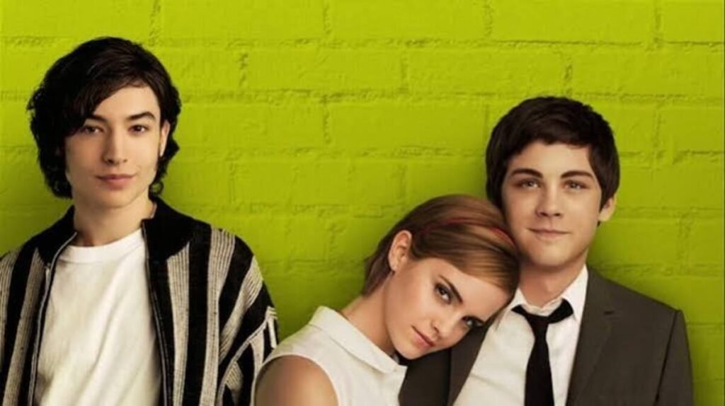 Filmes de amadurecimento: As produções contemporâneas que explicam a nova geração 7 Ezra Miller, Emma Watson apoiada no ombro de Logan Lerman em foto promocional sob fundo de tijolos verde-limão do filme As Vantagens de Ser Invisível.