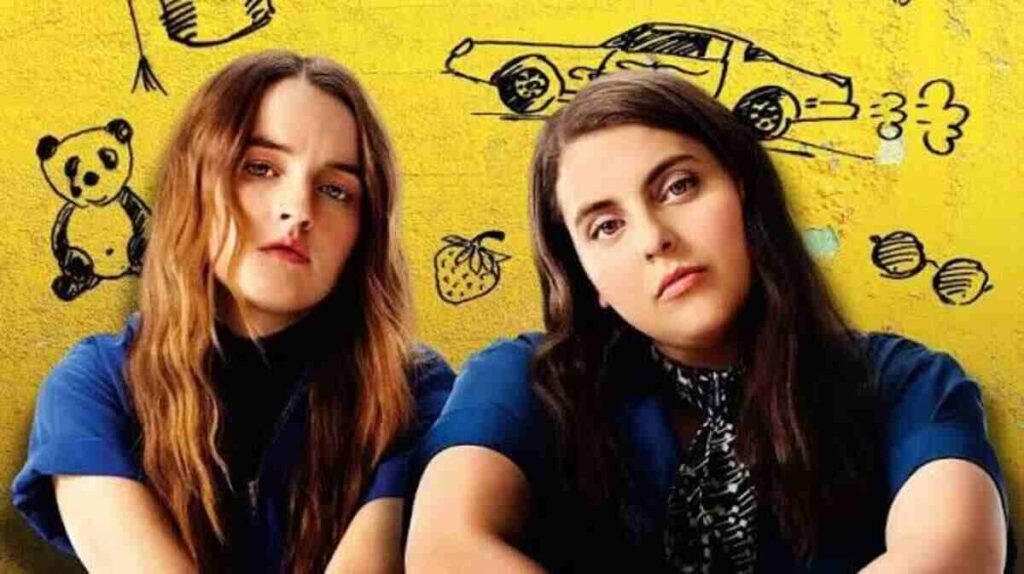 Filmes de amadurecimento: As produções contemporâneas que explicam a nova geração 3 As atrizes Beanie Feldstein e Kaitlyn Dever em pose confiante na arte promocional com fundo amarelo do filme Booksmart. A imagem focada na amizade feminina e em comédias voltadas para o amadurecimento estudantil é excelente para ilustrar críticas de cinema, listas de melhores filmes adolescentes contemporâneos e dicas de produções divertidas no blog.