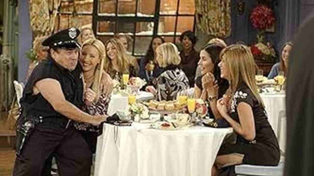Famosos na TV: Participações especiais em séries que você pode ter deixado passar 11 O ator Danny DeVito caracterizado como policial em cena cômica ao lado do elenco principal durante uma famosa participação especial de televisão. A imagem capturando o momento icônico de humor e cultura pop é excelente para ilustrar listas de curiosidades, bastidores de comédias e análises de episódios clássicos de séries no site.