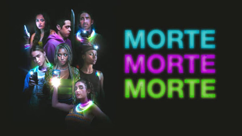 Filmes de amadurecimento: As produções contemporâneas que explicam a nova geração 11 Jovens iluminados por lanternas de celulares e colares de neon na escuridão ao lado do título do filme Morte Morte Morte escrito em letras coloridas sobre fundo preto.