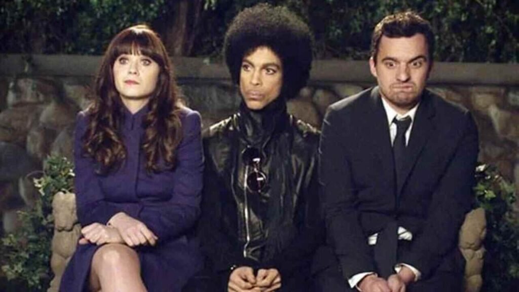 Famosos na TV: Participações especiais em séries que você pode ter deixado passar 3 Participação especial icônica do cantor Prince ao lado dos protagonistas em cena marcante de famosa série de comédia de televisão. A imagem de divulgação destacando momentos inusitados com grandes astros da música e da cultura pop é excelente para ilustrar críticas de episódios, listas de participações memoráveis e artigos de entretenimento no site.